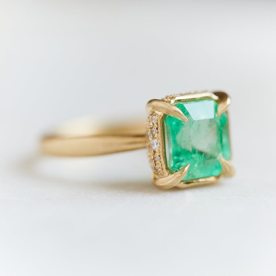 A 2.35ct Emerald ring with an 18k gold setting and band. Four gold prongs secure the Emerald to the setting. The setting is inlaid with .32ct diamonds.