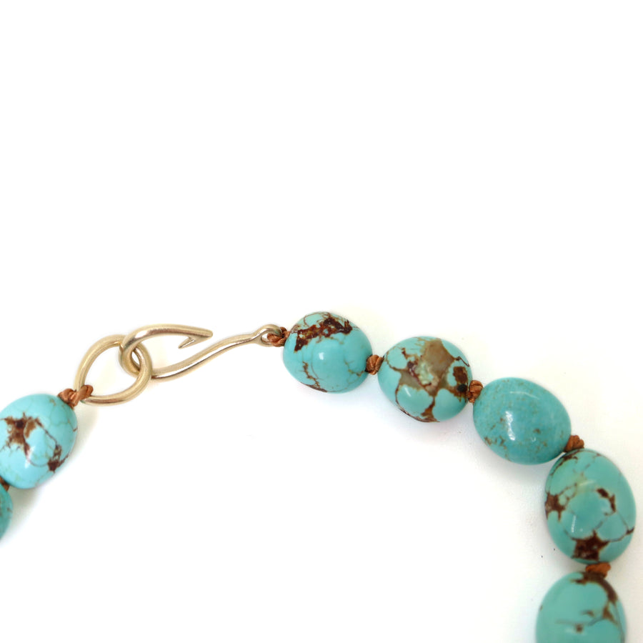 mottled kingman turquoise beads are strung on brown silk with 14k yellow gold fish hook clasp