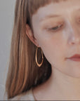 designer wearing her medium facet hoops in 14k rose gold with red lips and blonde hair with bangs