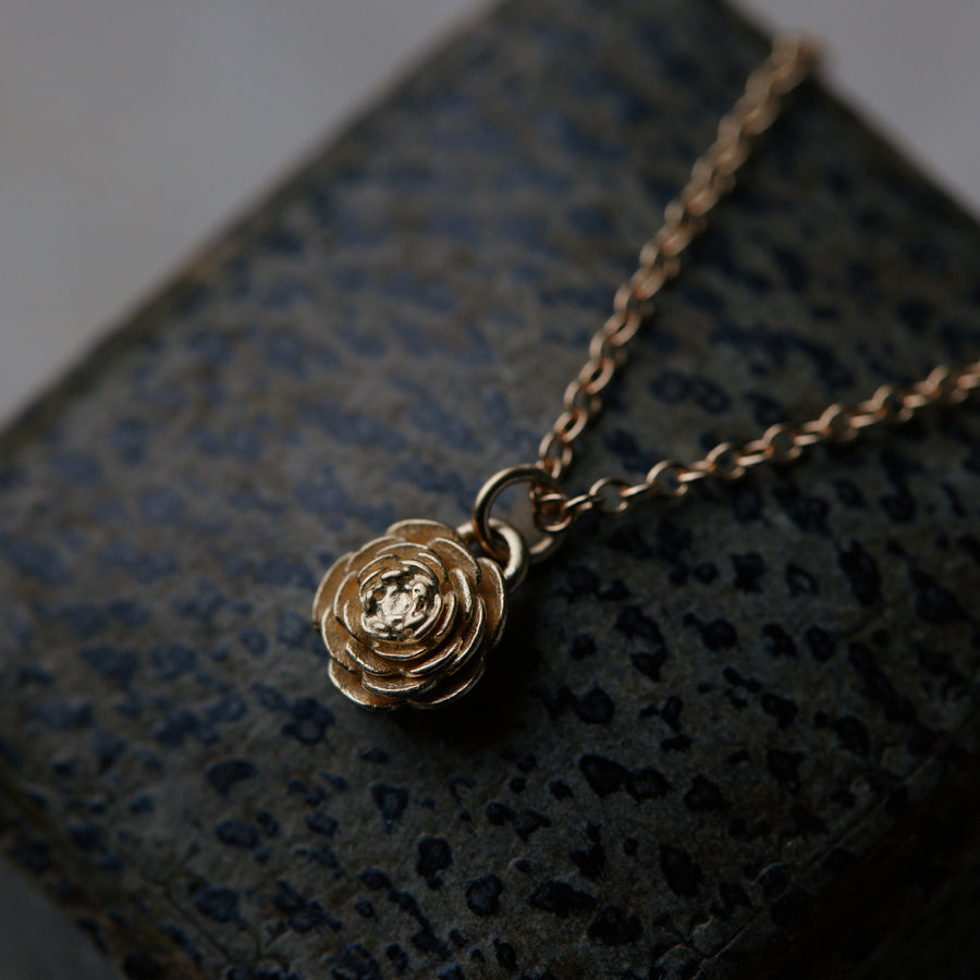 gold rose pendant necklace on leather jewelry box