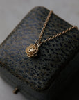 golden rose pendant necklace laying on leather jewelry box