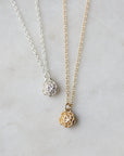 silver and gold rose garden pendant necklaces laying on marble