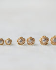 three pairs of gold rose garden studs in varying sizes, with diamonds in their centers.