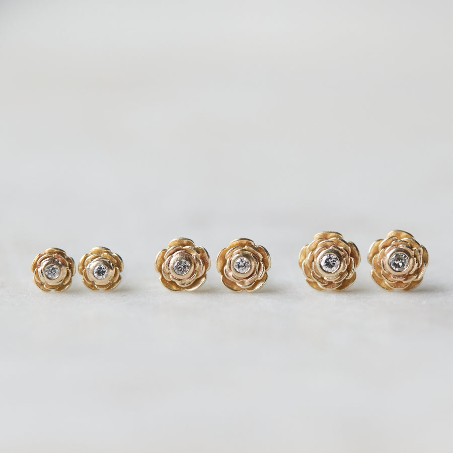 three pairs of gold rose garden studs in varying sizes, with diamonds in their centers.