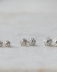 three pairs of silver rose garden studs in varying sizes, with diamonds in their centers.