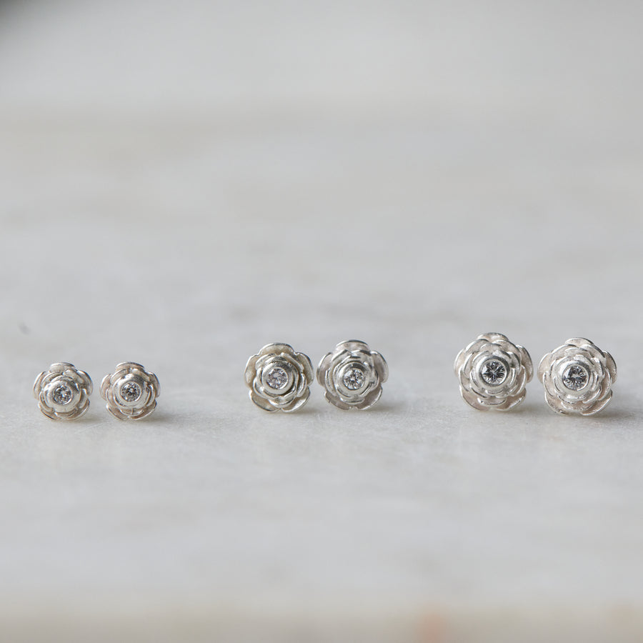 three pairs of silver rose garden studs in varying sizes, with diamonds in their centers.