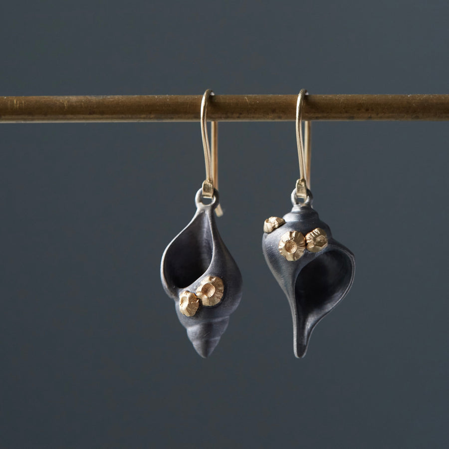 tulip and whelk spiral shells in black silver are adorned with gold barnacles and gold ear wires in handmade earrings