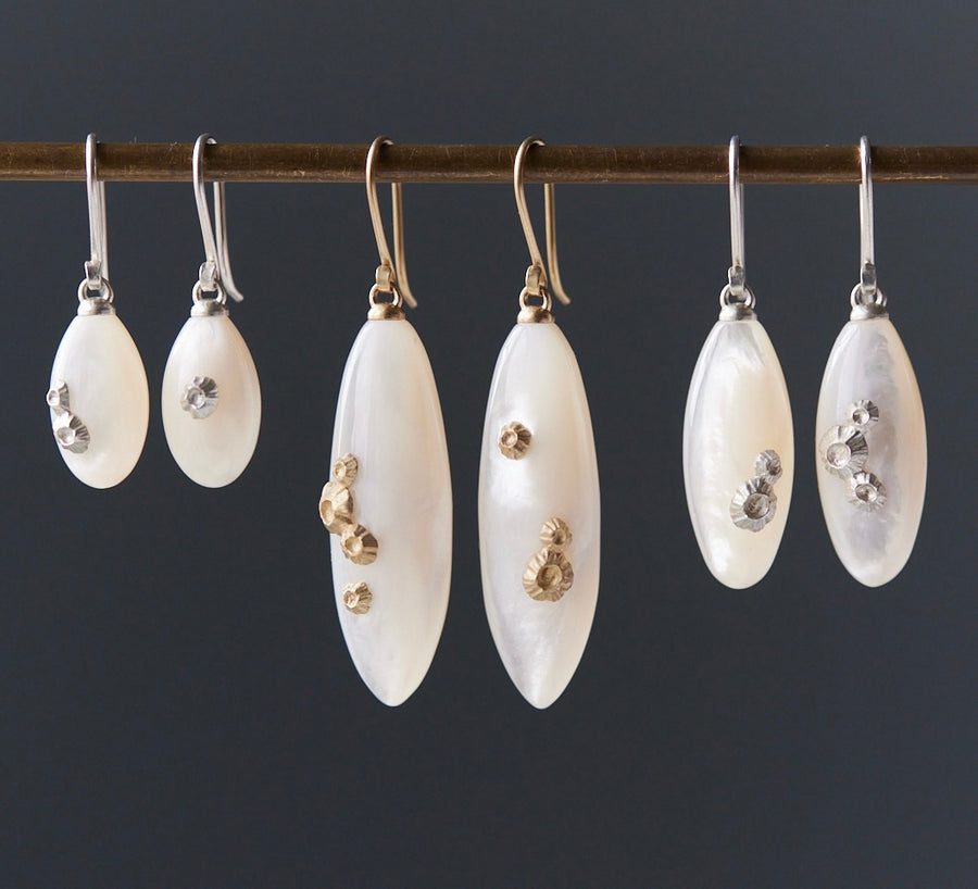 three pairs of mother of pearl drop earrings in sizes small, medium, and large, with either silver or gold barnacles