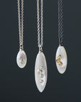 mother of pearl pendants on chains in varying metals, from bright sterling silver to oxidized silver + 14k gold combination, and in three sizes: little, medium, large.