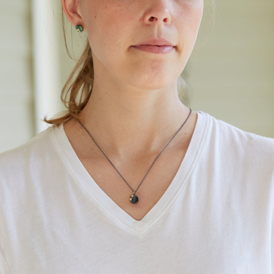 black spiral moon snail pendant necklace with gold barnacles on person