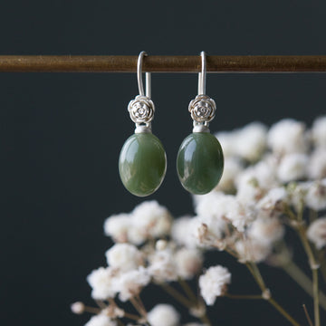 sage green jade oval beads hang beneath silver ear wires featuring little silver roses on them