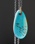 kingman turquoise pendant with inked illustration of a school of tiny fish on oxidized silver chain with gold details