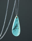 kingman turquoise teardrop bead with ink scrimshaw of codfish and little fishes. Necklace with gold and oxidized silver.