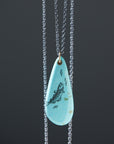 kingman turquoise teardrop bead with ink scrimshaw of codfish and little fishes. Necklace with gold and oxidized silver.