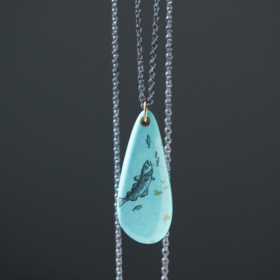 kingman turquoise teardrop bead with ink scrimshaw of codfish and little fishes. Necklace with gold and oxidized silver.