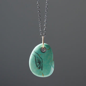 green kingman turquoise pendant on black chain with gold links. Hand scrimshawed in ink on turquoise.