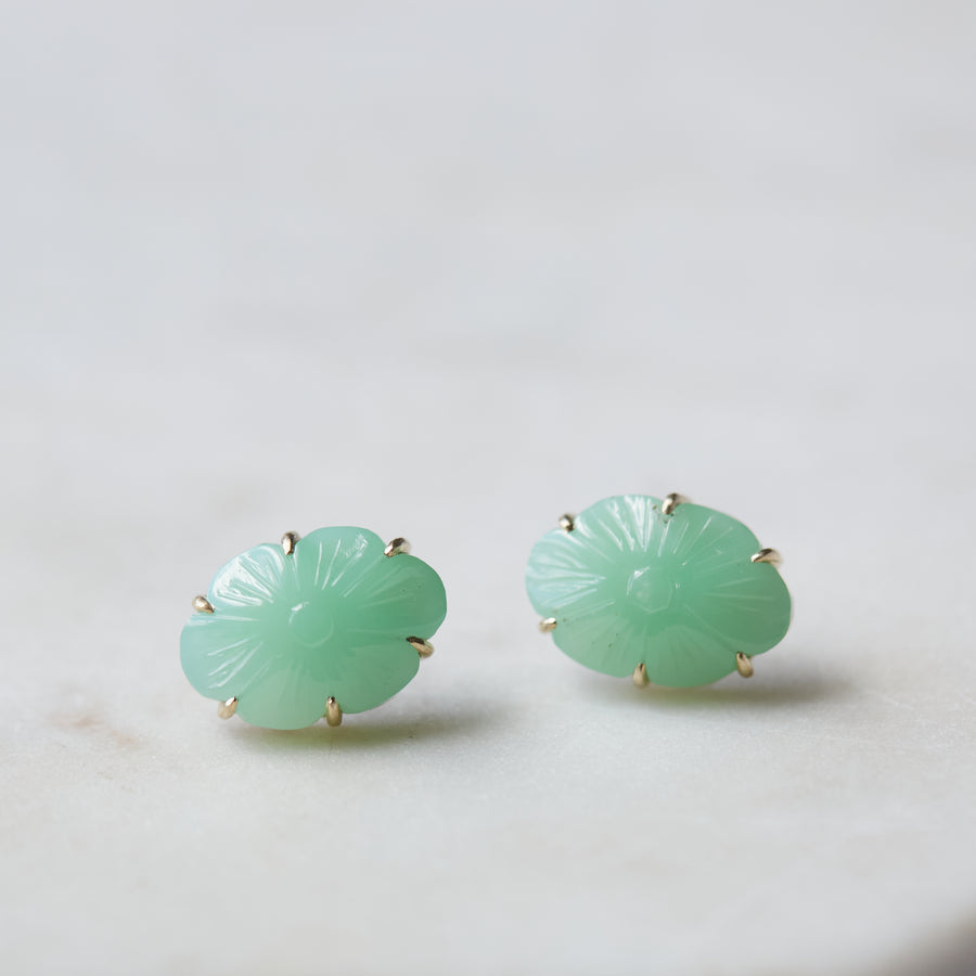 13.06ct Carved Chrysoprase Studs on a pale stone background. The Carved Chrysoprase is set with six 14k gold prongs. The Carved Chrysoprase is oval shaped with a carved flower motif. One of the studs is in profile to show the 14k gold post and bright silver stone seat.