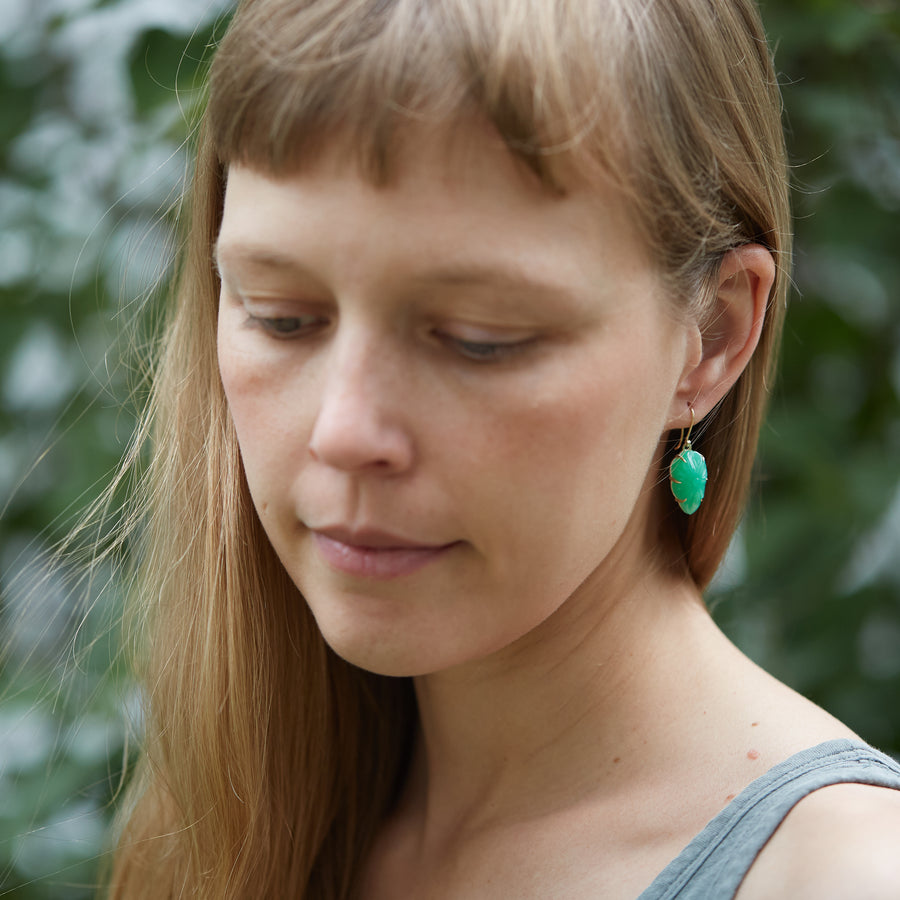 green chrysoprase earrings, carved like leaves, set with gold prongs. These earrings are shown on person.