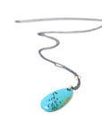 kingman turquoise pendant with inked illustration of a school of tiny fish on oxidized silver chain with gold details