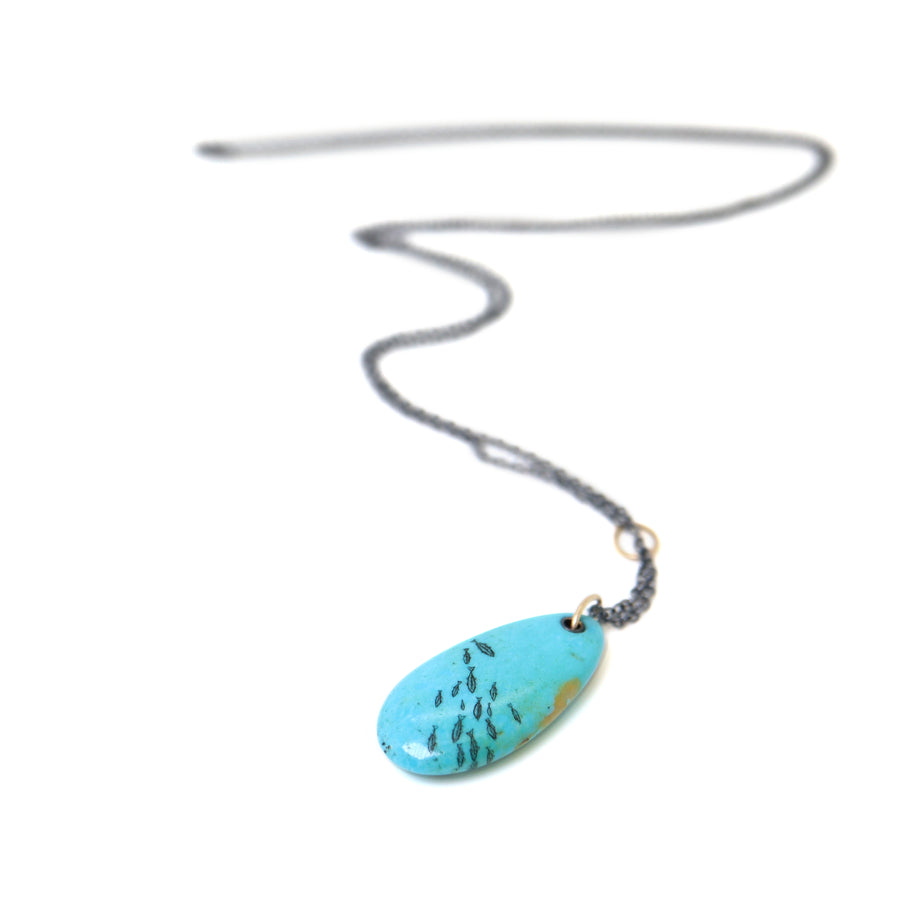 kingman turquoise pendant with inked illustration of a school of tiny fish on oxidized silver chain with gold details