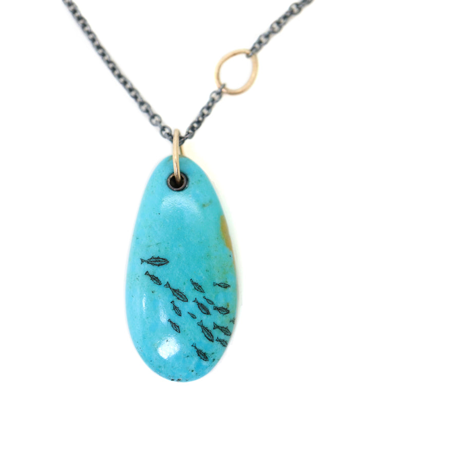 kingman turquoise pendant with inked illustration of a school of tiny fish on oxidized silver chain with gold details