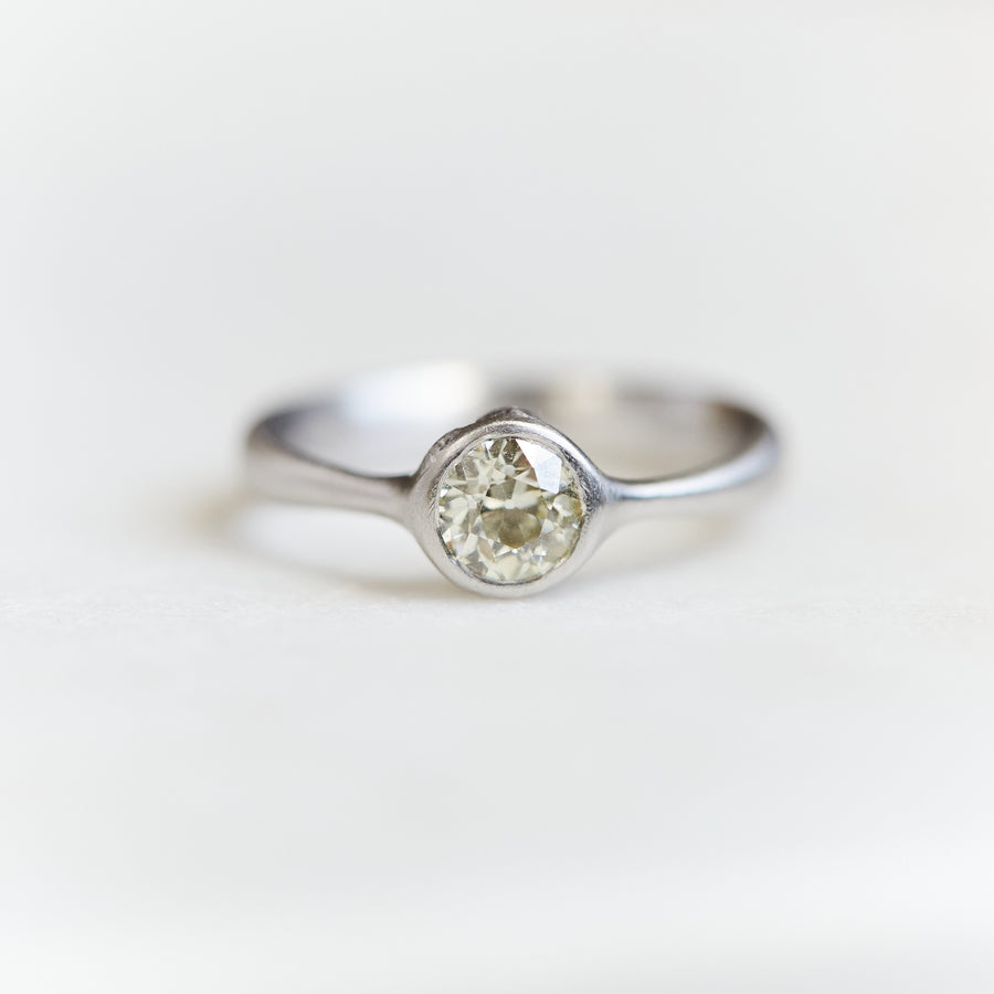 0.7ct Old European cut diamond ring in platinum on a white background. The diamond is set in a low profile with two barnacles peeking out of the setting.