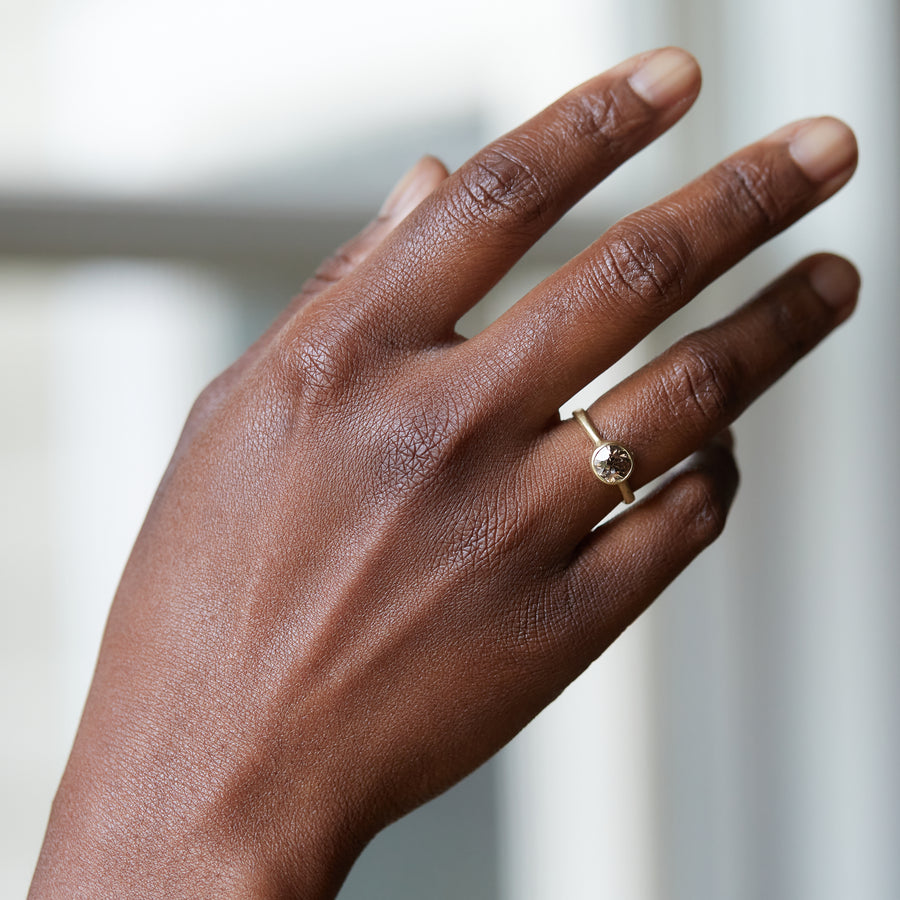 A 1.38ct diamond ring. The diamond has a chestnut hue and is set in 18k gold with an 18k gold band. The setting is encrusted with 14k gold barnacles. The ring is viewed off center and is set on a white background. Photographed on person on the ring finger.