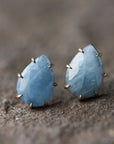 teardrop aquamarine faceted stones set in earring studs with gold prongs