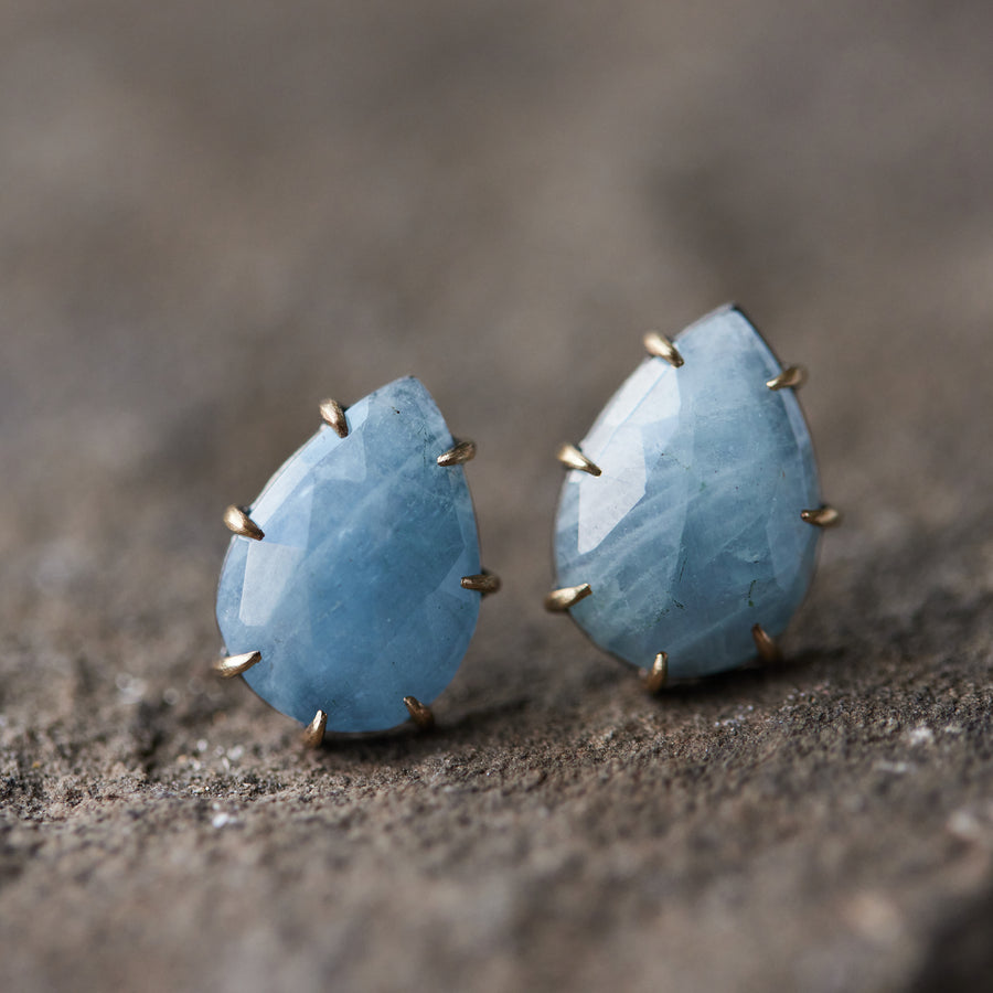 teardrop aquamarine faceted stones set in earring studs with gold prongs