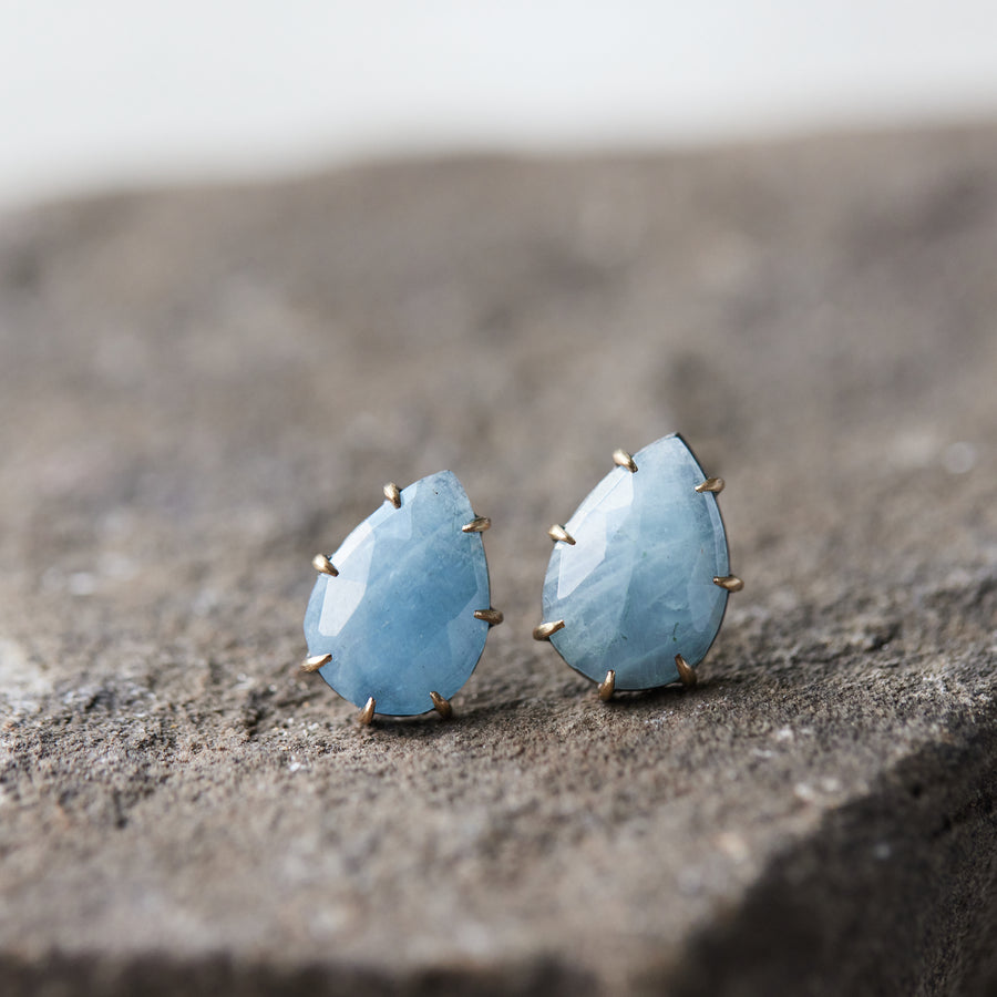 teardrop aquamarine faceted stones set in earring studs with gold prongs