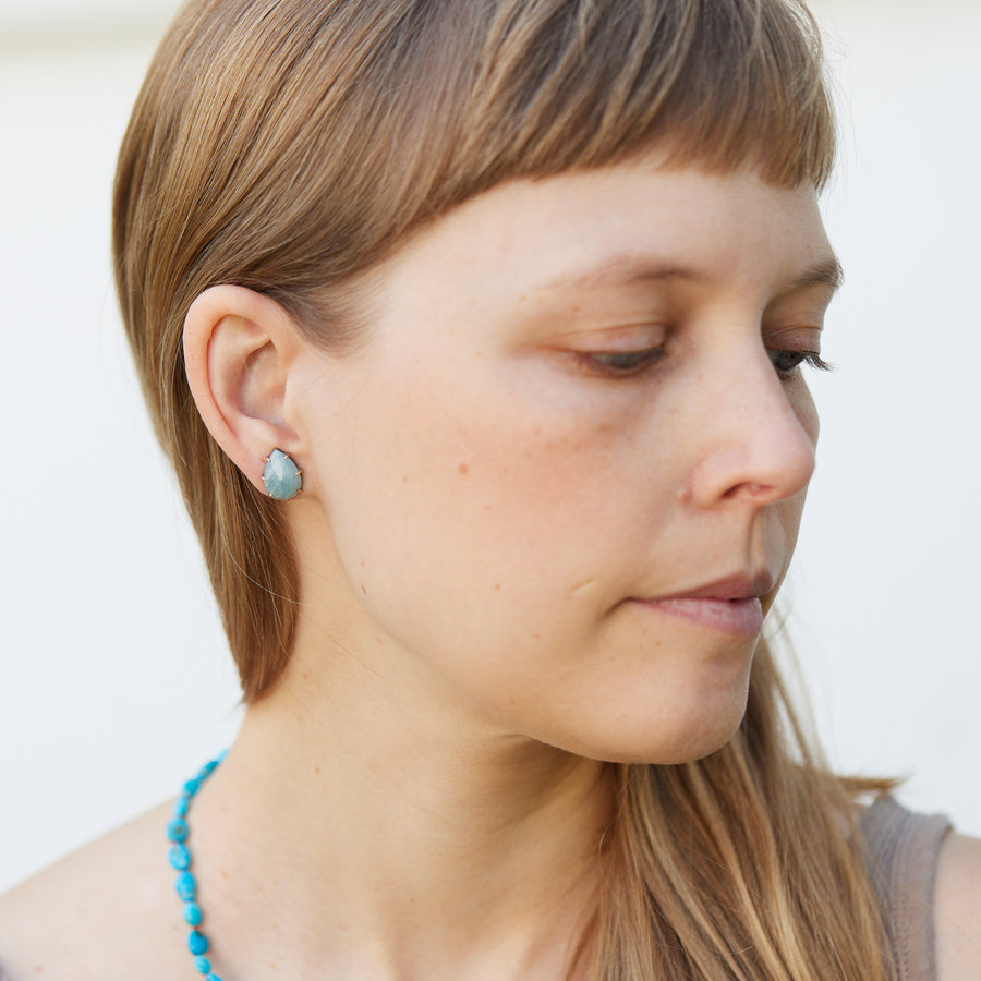 teardrop aquamarine faceted stones set in earring studs with gold prongs