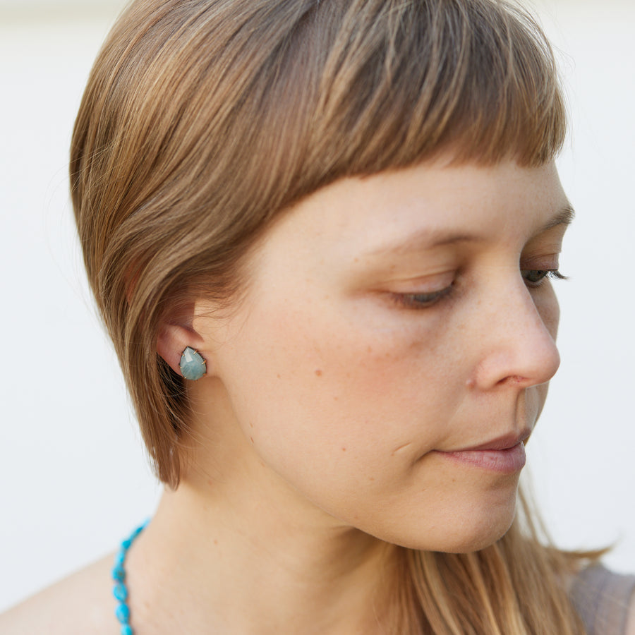 teardrop aquamarine faceted stones set in earring studs with gold prongs