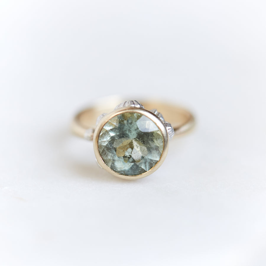 A 2.74ct tourmaline ring. The tourmaline is a deep green and is set in 14k gold with a 14k gold band. The rsetting is encrusted with bright sterling silver barnacles. The ring is viewed from the front.