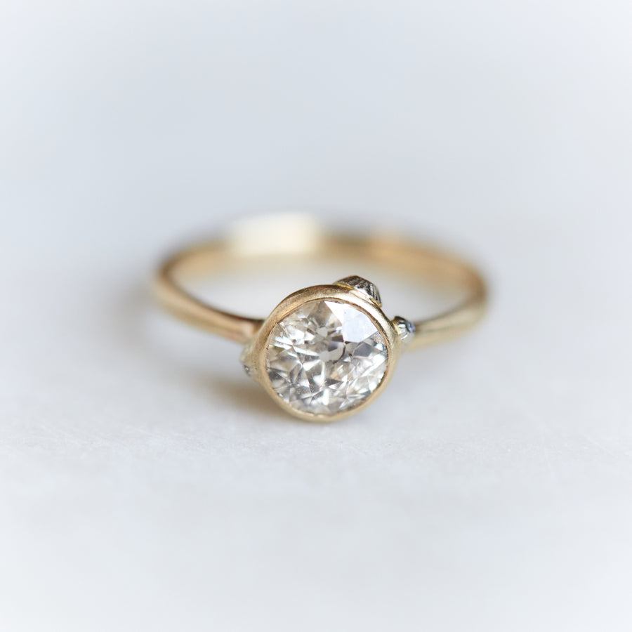 A 1.07ct Old Mine Cut diamond ring. The diamond is set in 10k gold with a tapered 10k gold band The setting is encrusted with bright sterling silver barnacles. The barnacles are inlaid with tiny diamonds. The ring is viewed from the front and is on a white background.