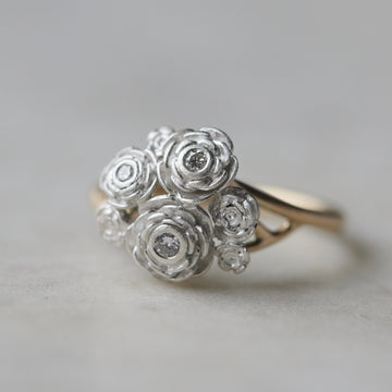 a bouquet of silver roses has three little diamonds set in them. the band is gold.