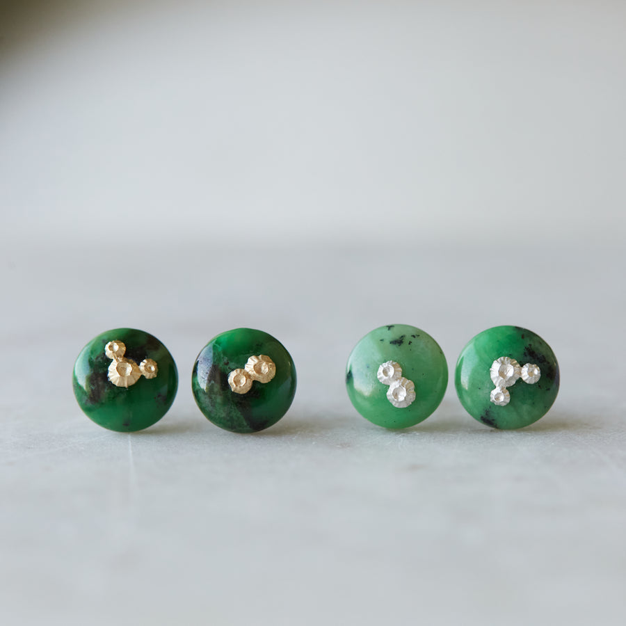 two pairs of green garnet earring studs, the left pair has gold barnacles and the right pair has silver barnacles.