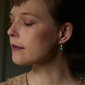 flashing with blue, grey labradorite cones hang beneath silver ear wires and silver roses. Shown on person.