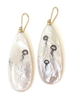 long teadrop mother of pearl earrings have gold ear wires and 3 jellyfish hand etched into the surface in black ink. A 4th jellyfish is on the back of the left earring, with the tentacles reach over onto the front.