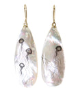 long teadrop mother of pearl earrings have gold ear wires and 3 jellyfish hand etched into the surface in black ink. A 4th jellyfish is on the back of the left earring, with the tentacles reach over onto the front.