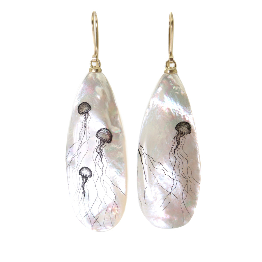 long teadrop mother of pearl earrings have gold ear wires and 3 jellyfish hand etched into the surface in black ink. A 4th jellyfish is on the back of the left earring, with the tentacles reach over onto the front.