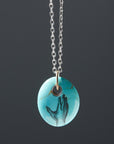 kingman turquoise bead pendant necklace on silver chain with gold bail. A scrimshaw hand is inked to the front.