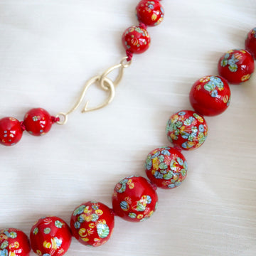 detail of necklace made from patterned red vintage glass beads with red silk and gold fish hook clasp