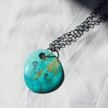 grand kingman turquoise pendant on black chain with gold bail. jellyfish scrimshaw inked on both sides.