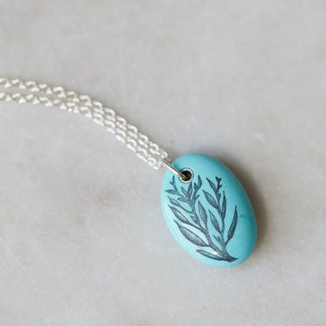 kingman turquoise pendant with inked illustration of seaweed on silver chain