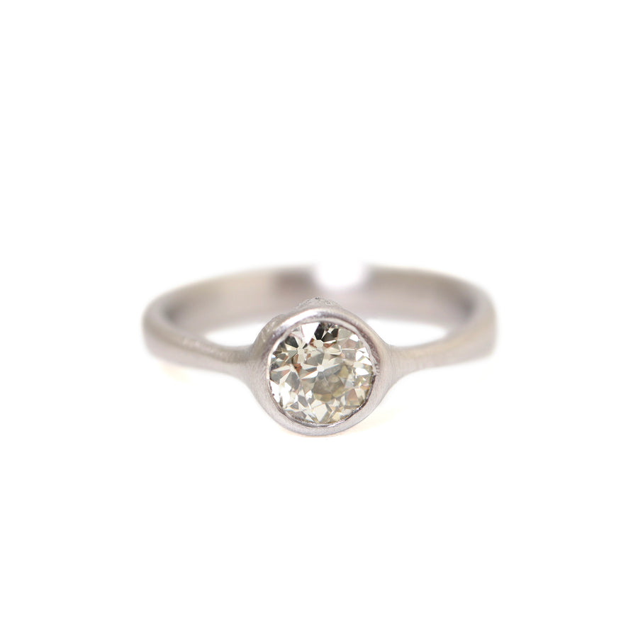 0.7ct Old European cut diamond ring in platinum on a white background. The diamond is set in a low profile with two barnacles peeking out of the setting.