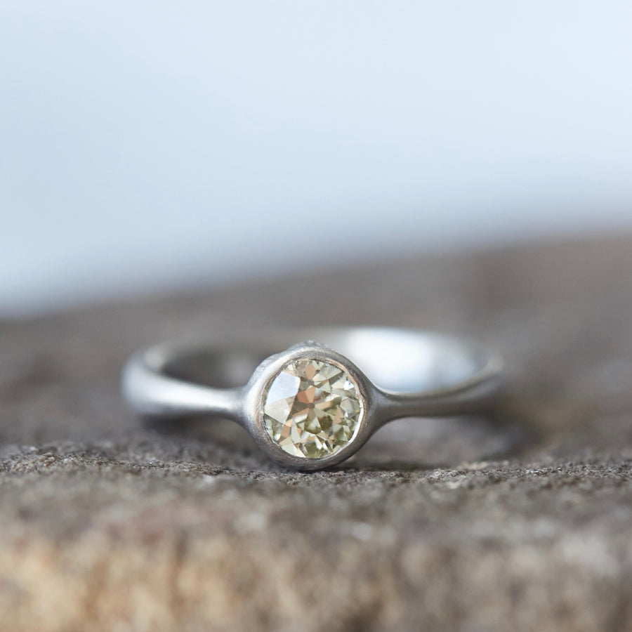 0.7ct Old European cut diamond ring in platinum on a white background. The diamond is set in a low profile with two barnacles peeking out of the setting.