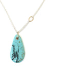 kingman turquoise pendant of scrimshaw of hand. Gold link with silver chain.