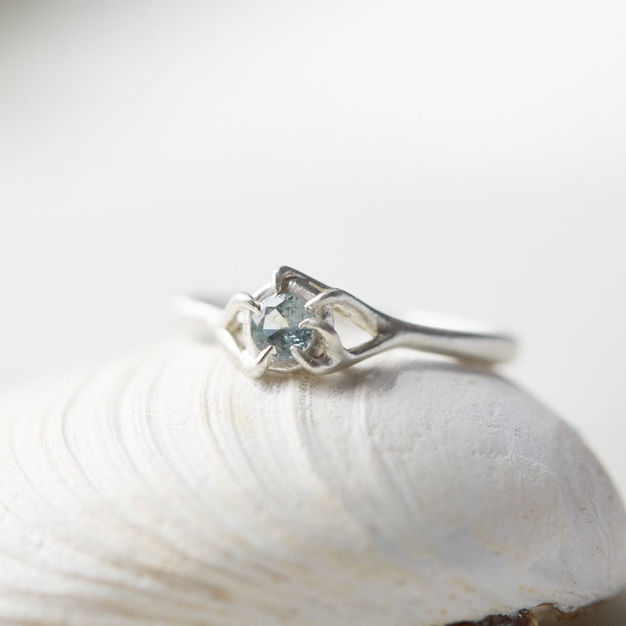 0.33ct pale blue Montana sapphire ring in bright sterling silver on a white background. the setting encircles the sapphire like branches.