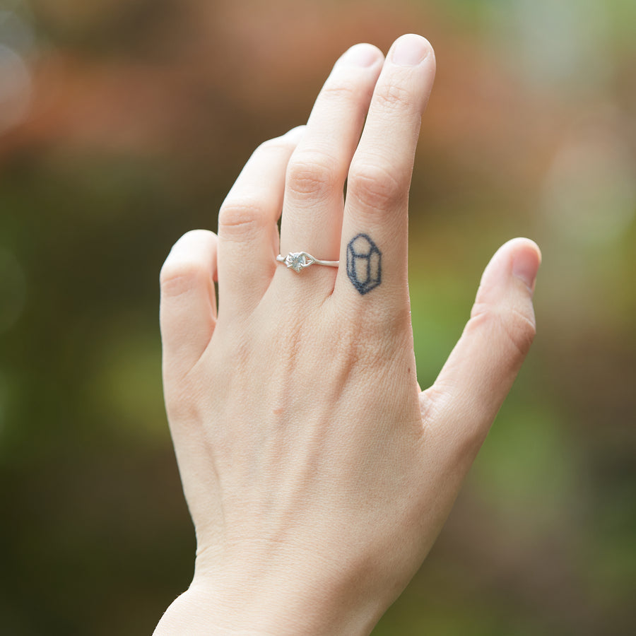 0.33ct pale blue Montana sapphire ring in bright sterling silver on a white background. the setting encircles the sapphire like branches. on hand.