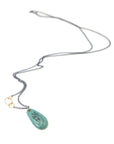 green turquoise teardrop bead with gold link and black chain. a scrimshaw hand is inked to the surface.